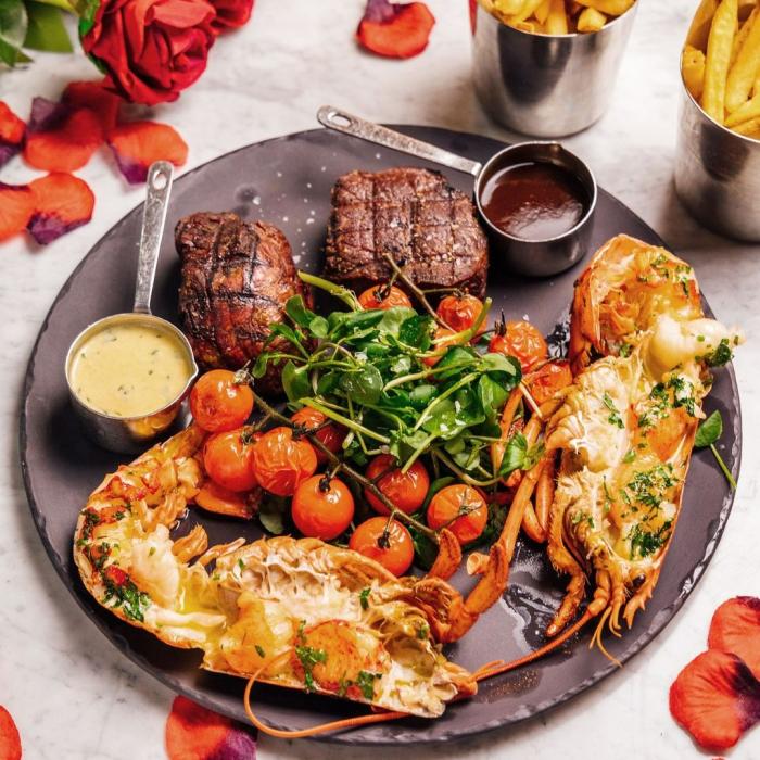 Plate of surf and turf surrounded by rose petals