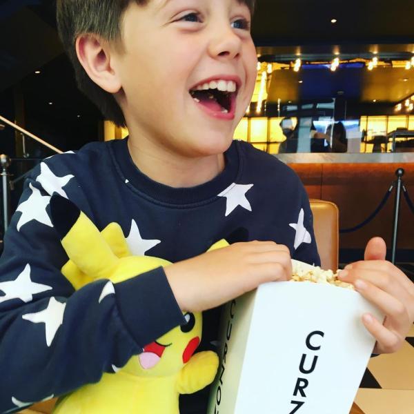 Smiling boy with popcorn and a Pokemon toy